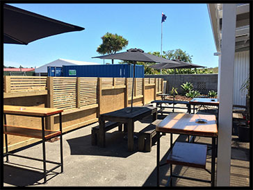 Sunny outdoor deck with tables and umbrellas at Caroline's Boatshed